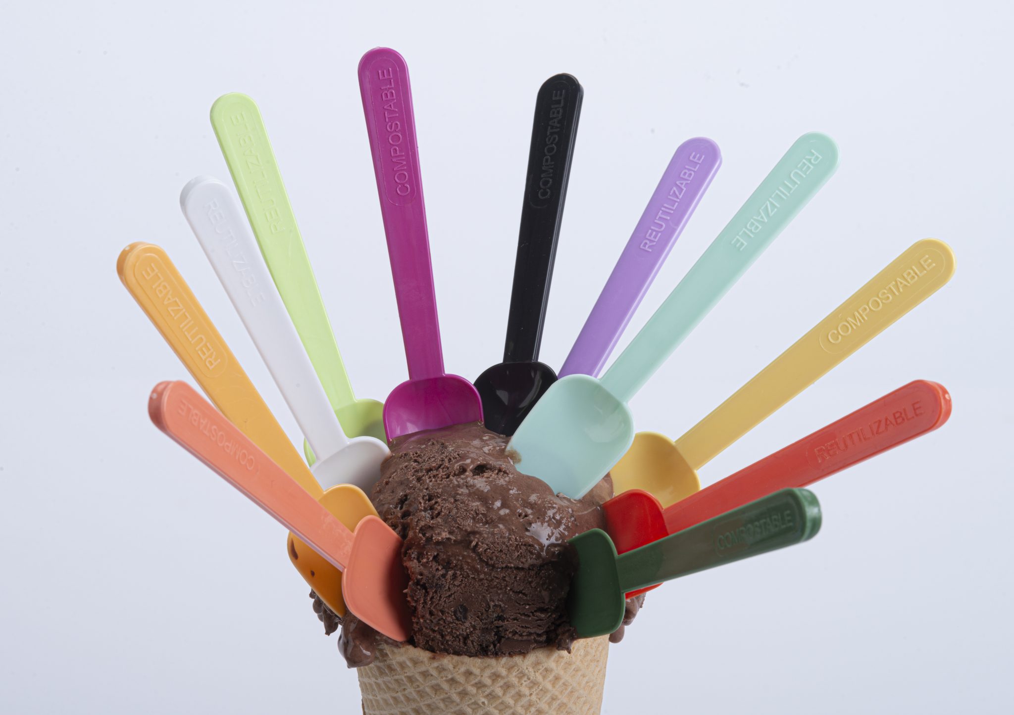 Cucharitas reutilizables y compostables de diferentes colores en helado de chocolate